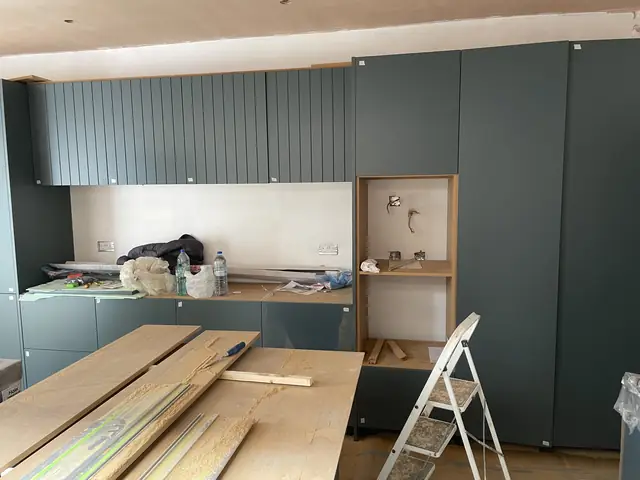 Detailed view of dark green kitchen cabinet installation in progress.