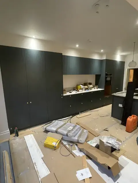 Kitchen under renovation with dark cabinets and construction debris throughout the space.
